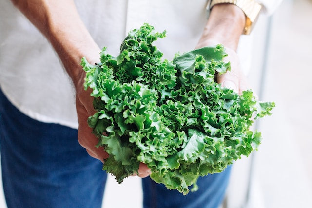 A selection of vitamin K-rich foods including leafy greens, broccoli, and avocado arranged on a wooden table, emphasizing natural nutrient sources.