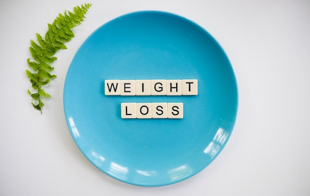Colorful plate of fresh vegetables, fruits, and whole grains arranged on a wooden table, symbolizing a balanced and healthy diet for improved well-being.